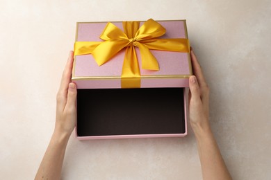 Photo of Woman opening gift box on light background, closeup