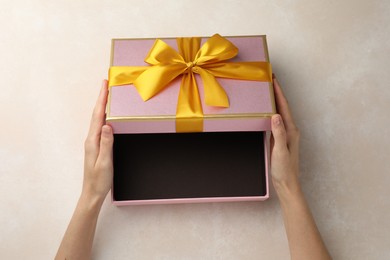 Photo of Woman opening gift box on light background, closeup