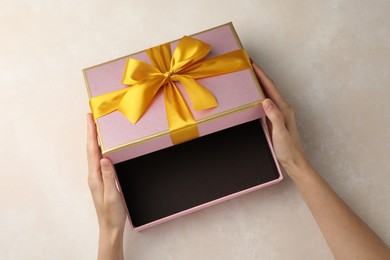Photo of Woman opening gift box on light background, closeup