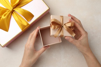 Photo of Woman opening gift box on light background, closeup