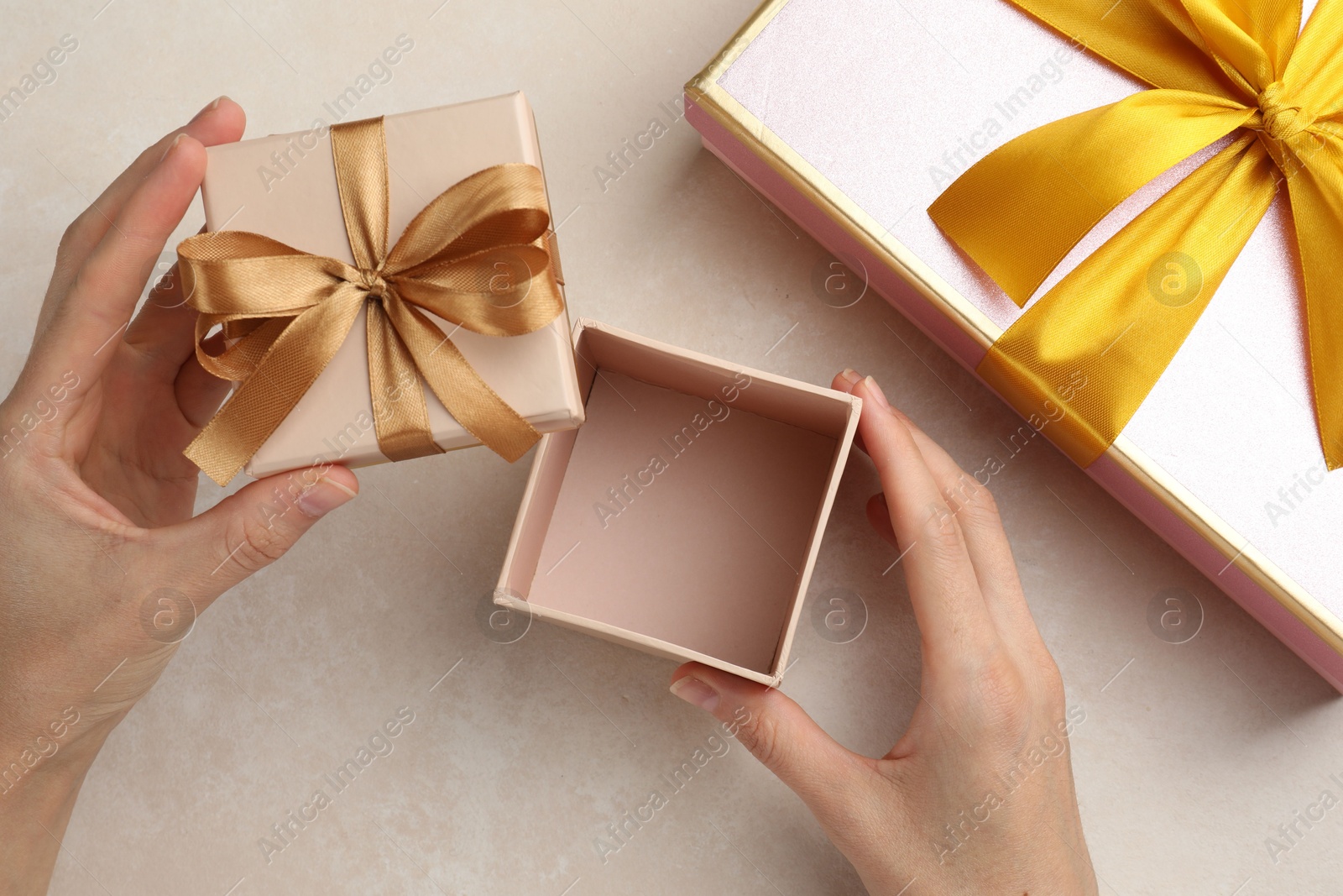 Woman opening gift box on light background, closeup Photo of Woman opening gift box on light background, closeup