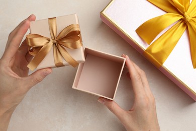 Photo of Woman opening gift box on light background, closeup