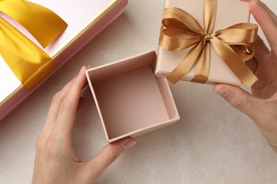 Photo of Woman opening gift box on light background, closeup