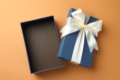 Photo of Open gift box with beautiful lid on orange background, top view