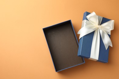 Photo of Open gift box with beautiful lid on orange background, top view. Space for text