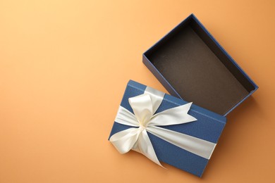 Photo of Open gift box with beautiful lid on orange background, top view. Space for text