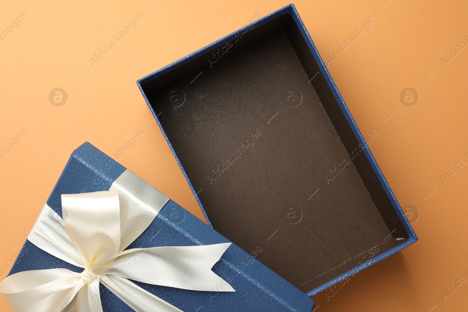 Photo of Open gift box with beautiful lid on orange background, top view
