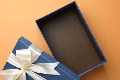 Photo of Open gift box with beautiful lid on orange background, top view