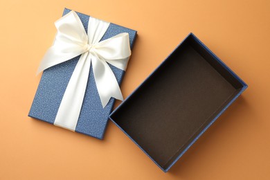 Photo of Open gift box with beautiful lid on orange background, top view