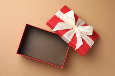 Photo of Opened gift box with beautiful lid on beige background, top view
