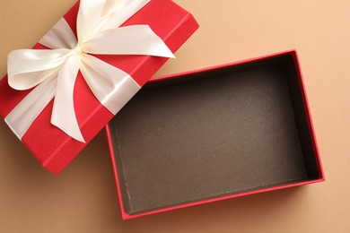 Photo of Opened gift box with beautiful lid on beige background, top view