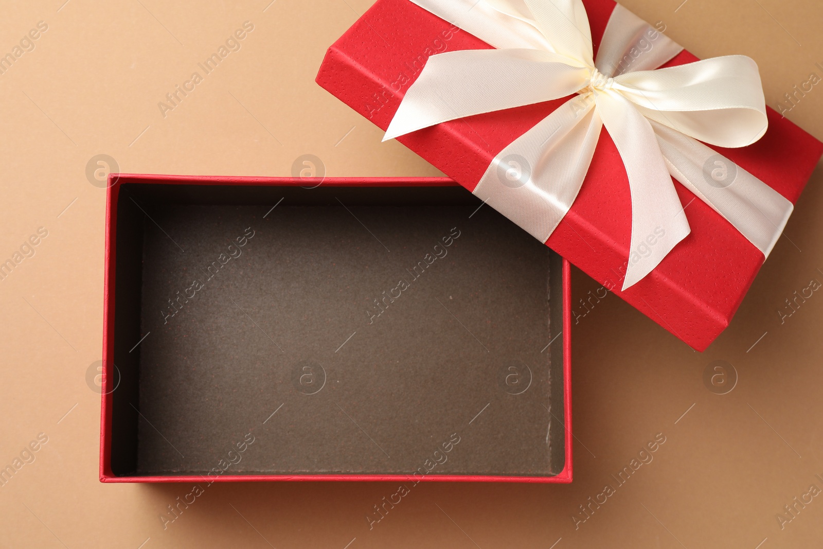 Photo of Opened gift box with beautiful lid on beige background, top view