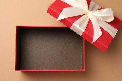 Photo of Opened gift box with beautiful lid on beige background, top view