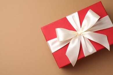 Photo of Gift box with beautiful bow on beige background, top view. Space for text
