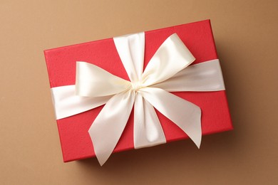 Photo of Gift box with beautiful bow on beige background, top view