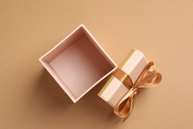 Photo of Opened gift box with beautiful lid on beige background, top view