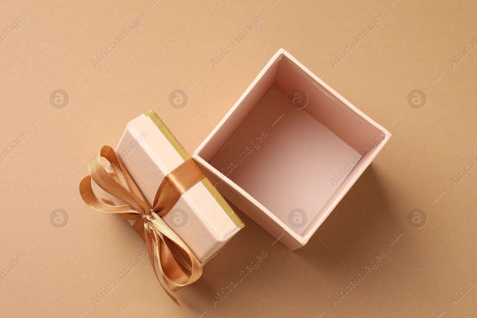 Photo of Opened gift box with beautiful lid on beige background, top view