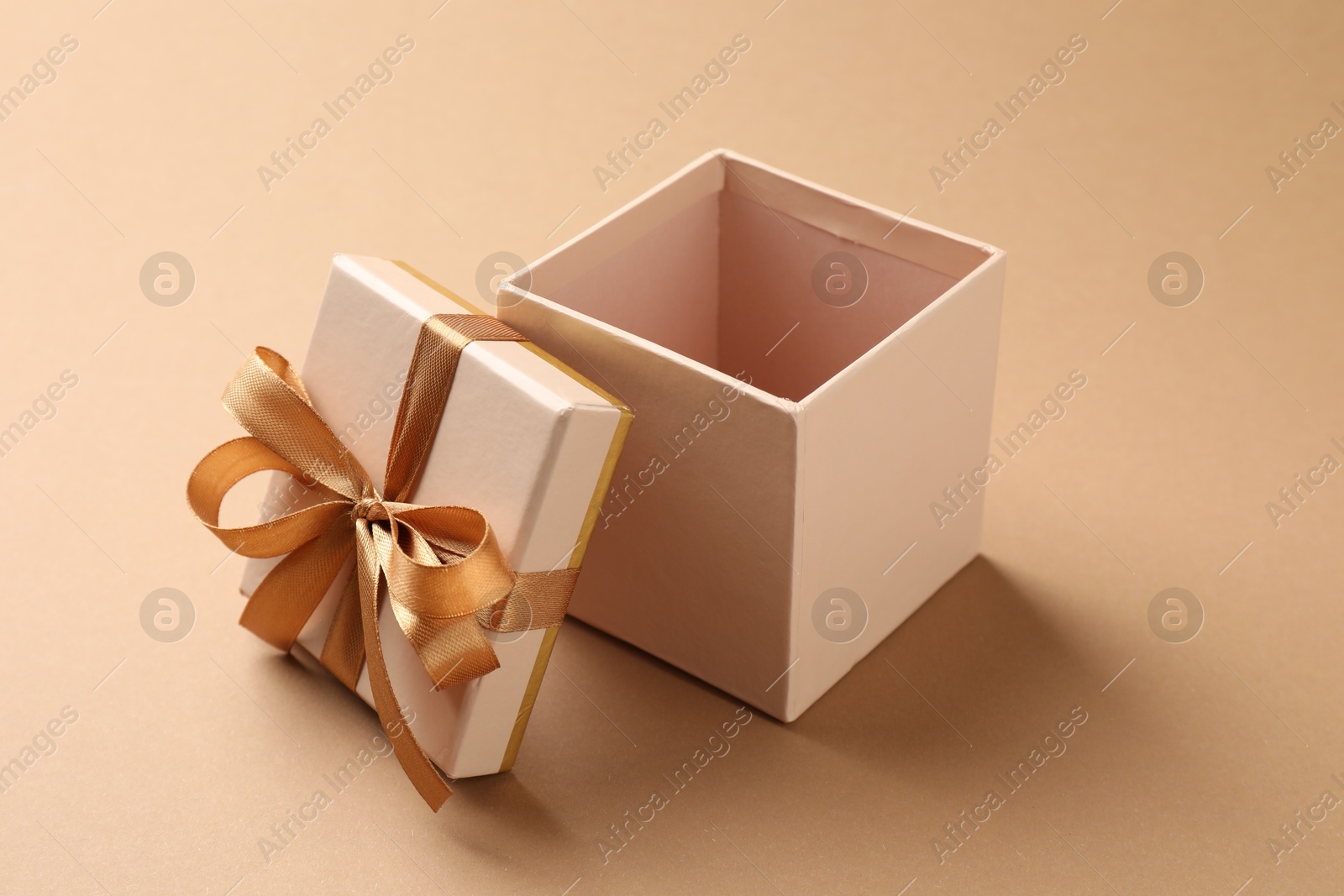 Opened gift box with beautiful lid on beige background, closeup Photo of Opened gift box with beautiful lid on beige background, closeup