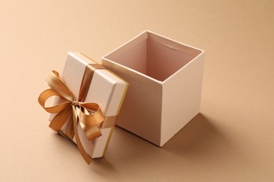 Photo of Opened gift box with beautiful lid on beige background, closeup