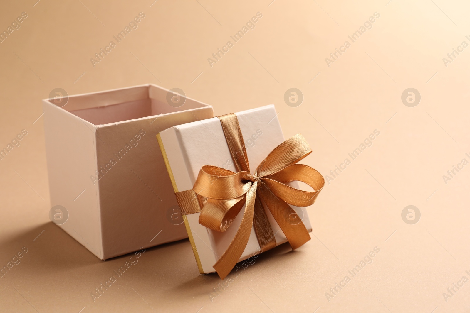 Photo of Opened gift box with beautiful lid on beige background, closeup. Space for text