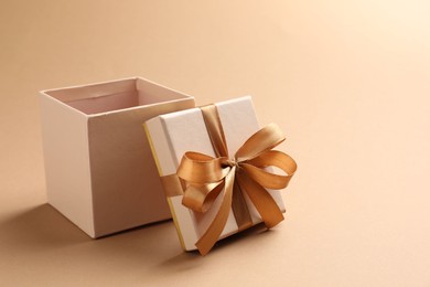 Photo of Opened gift box with beautiful lid on beige background, closeup. Space for text