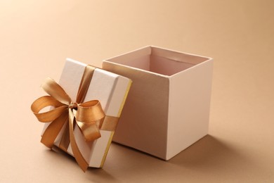 Photo of Opened gift box with beautiful lid on beige background, closeup