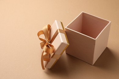 Photo of Opened gift box with beautiful lid on beige background, closeup. Space for text