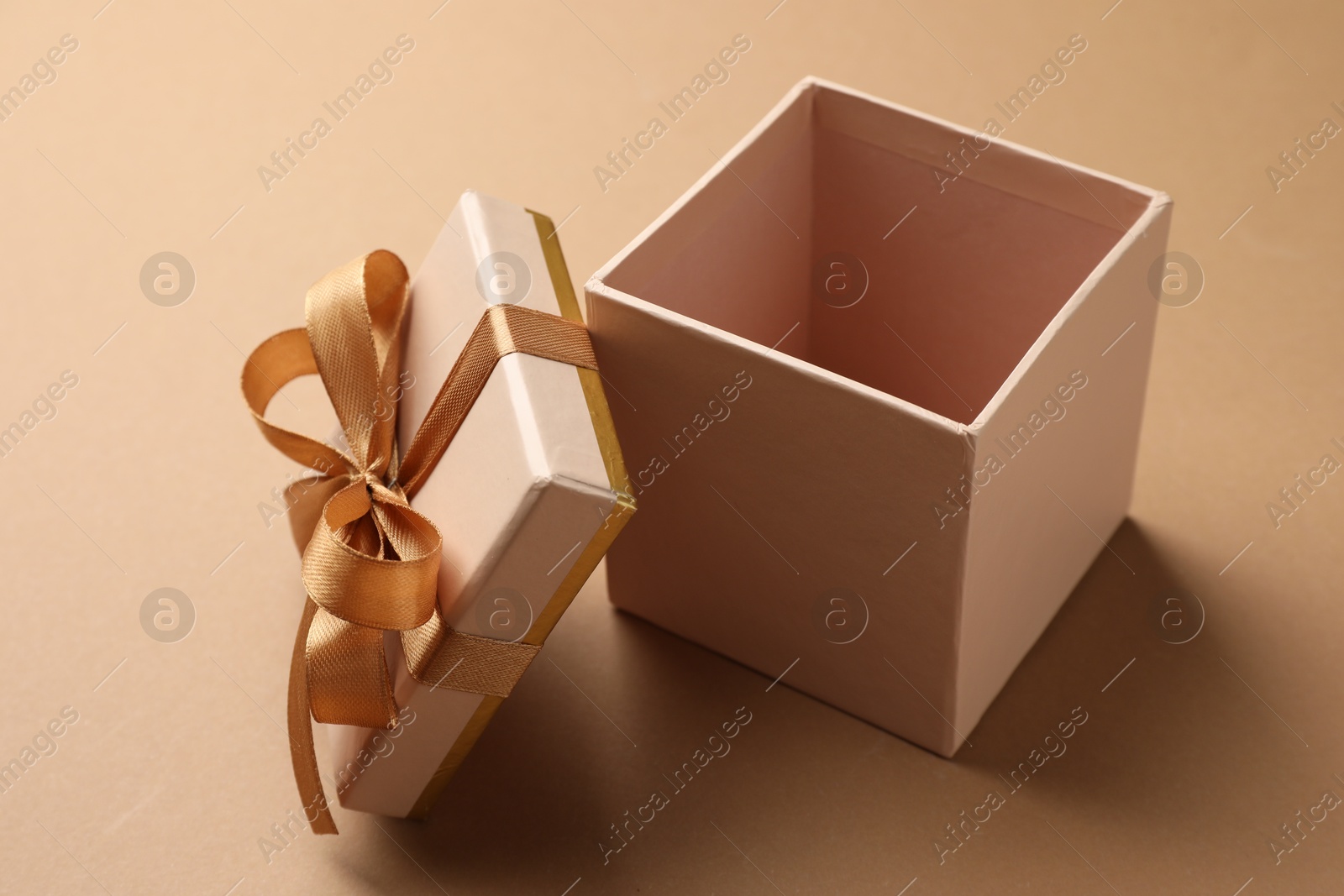 Photo of Opened gift box with beautiful lid on beige background, closeup
