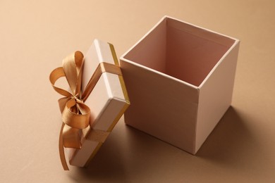 Photo of Opened gift box with beautiful lid on beige background, closeup