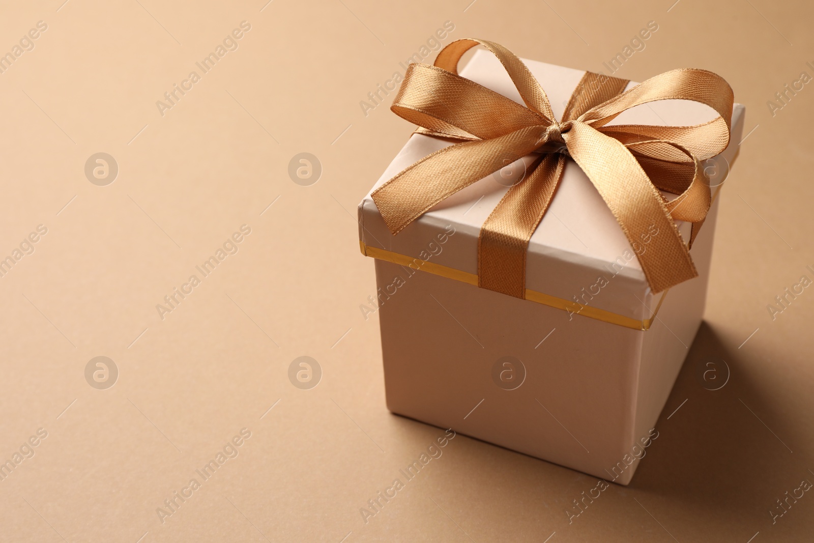 Photo of Gift box with beautiful bow on beige background, closeup. Space for text
