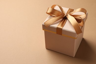 Photo of Gift box with beautiful bow on beige background, closeup. Space for text