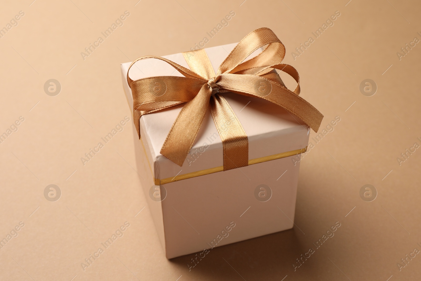 Photo of Gift box with beautiful bow on beige background, closeup