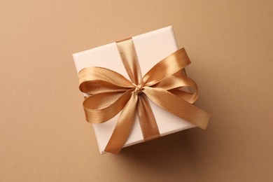 Photo of Gift box with beautiful bow on beige background, top view