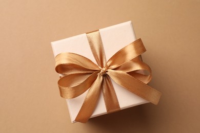 Photo of Gift box with beautiful bow on beige background, top view