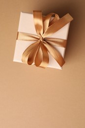 Photo of Gift box with beautiful bow on beige background, top view. Space for text