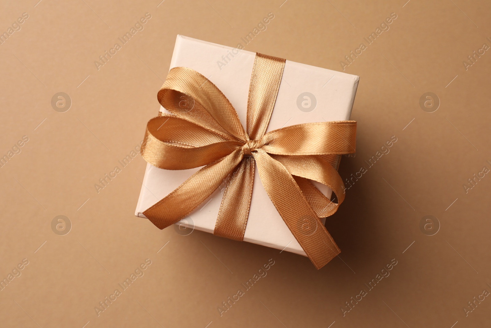 Photo of Gift box with beautiful bow on beige background, top view