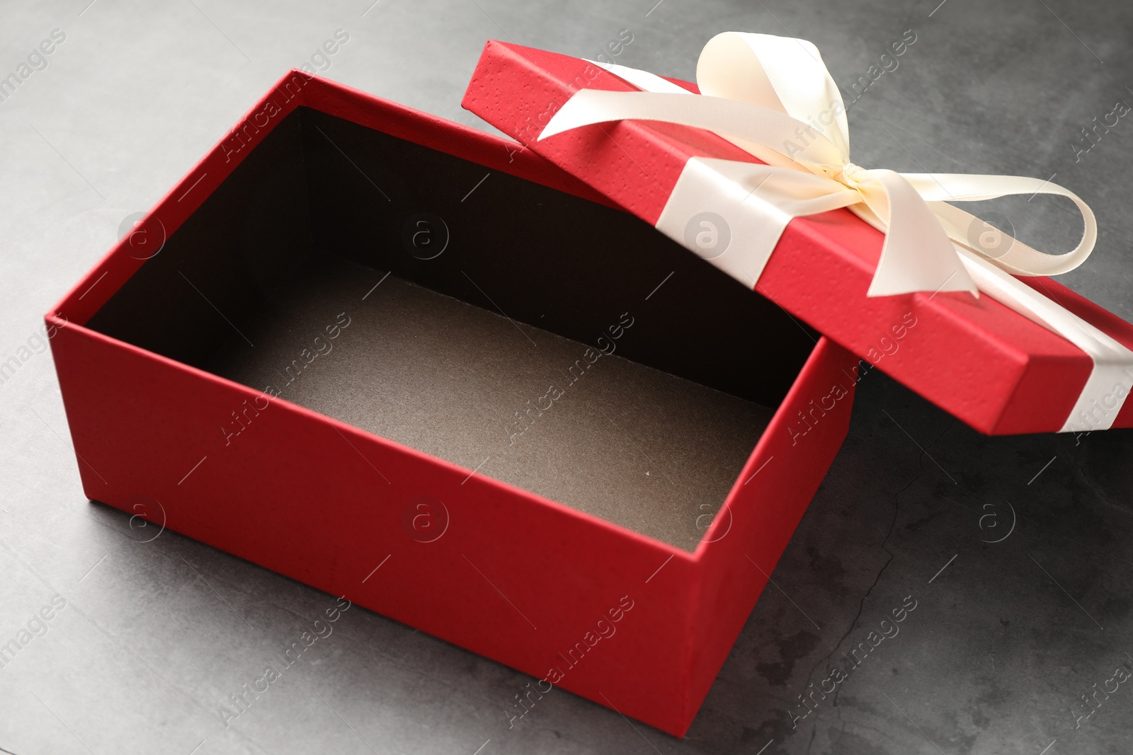 Opened gift box with beautiful lid on grey table, closeup Photo of Opened gift box with beautiful lid on grey table, closeup