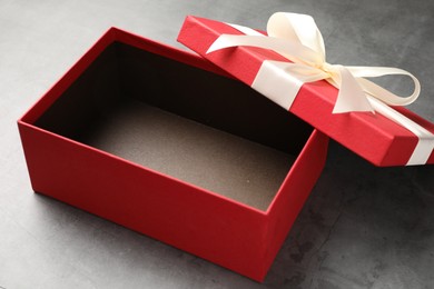 Photo of Opened gift box with beautiful lid on grey table, closeup
