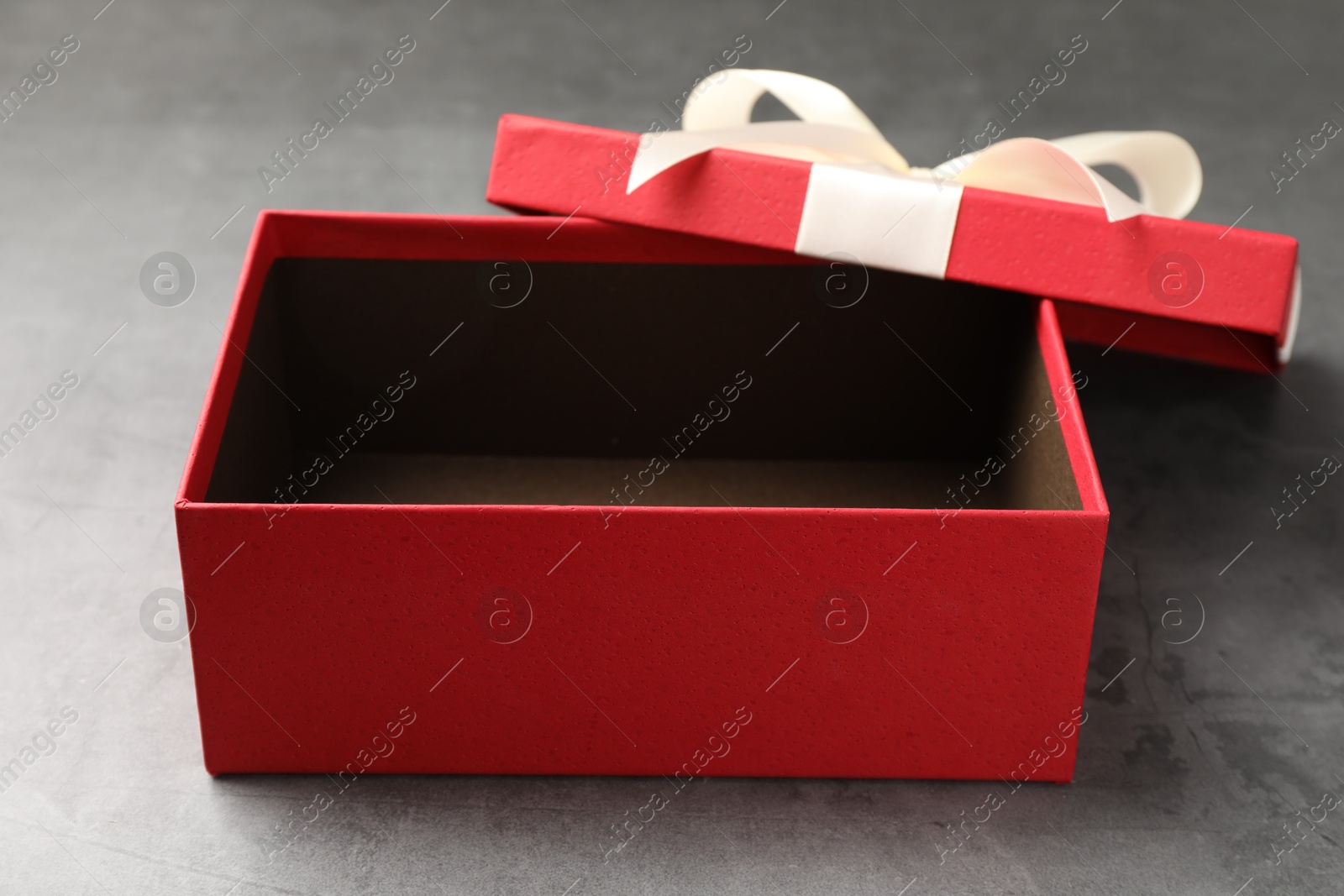 Opened gift box with beautiful lid on grey table, closeup Photo of Opened gift box with beautiful lid on grey table, closeup