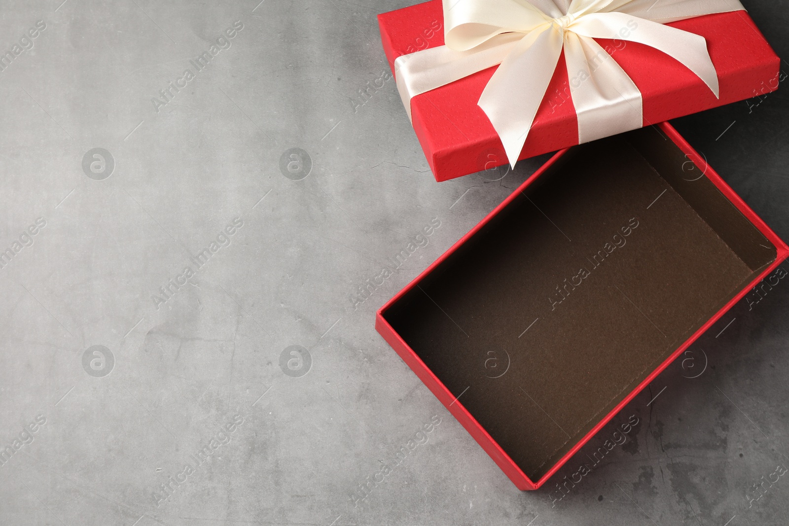 Opened gift box with beautiful lid on grey table, top view. Space for text Photo of Opened gift box with beautiful lid on grey table, top view. Space for text
