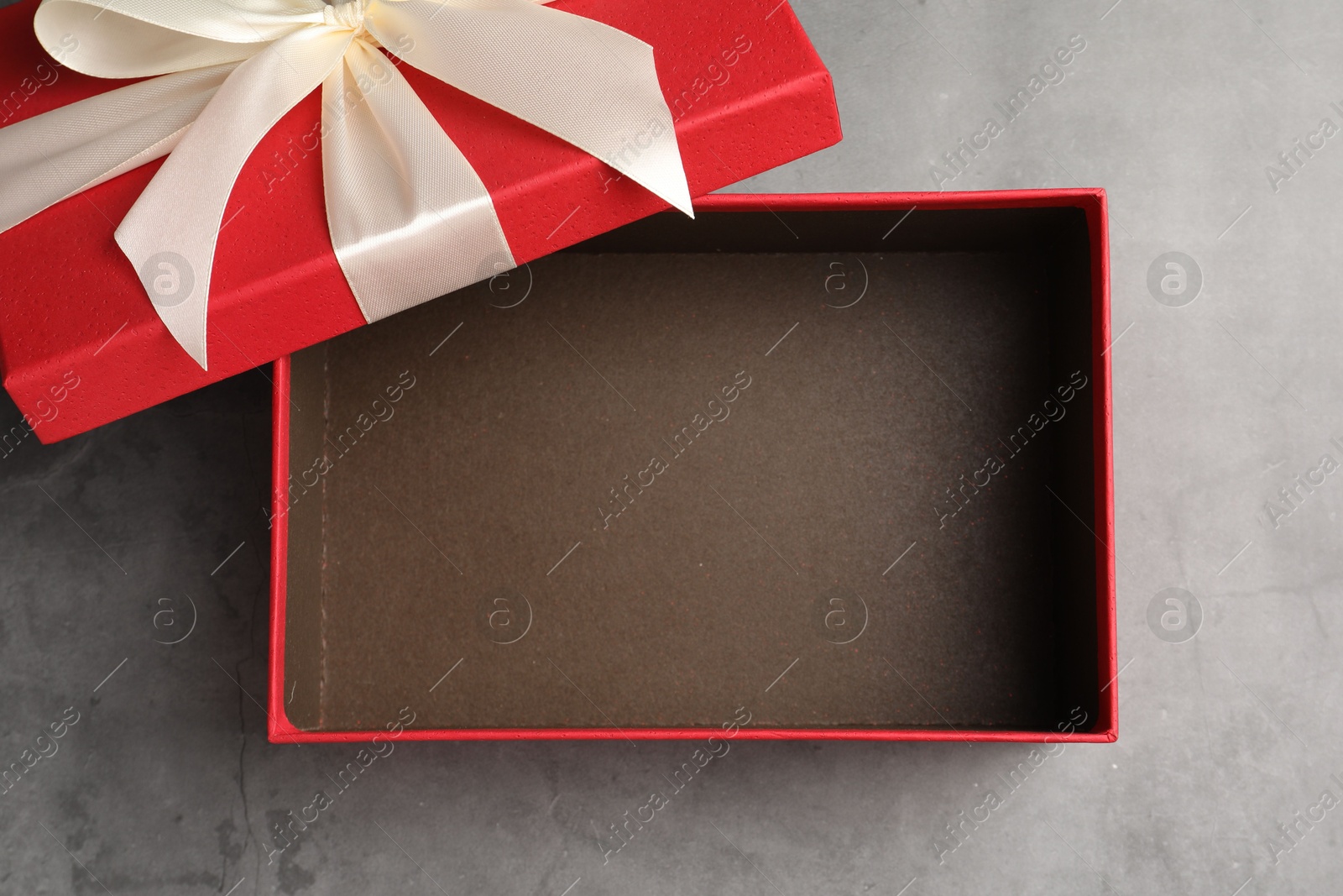 Opened gift box with beautiful lid on grey table, top view Photo of Opened gift box with beautiful lid on grey table, top view