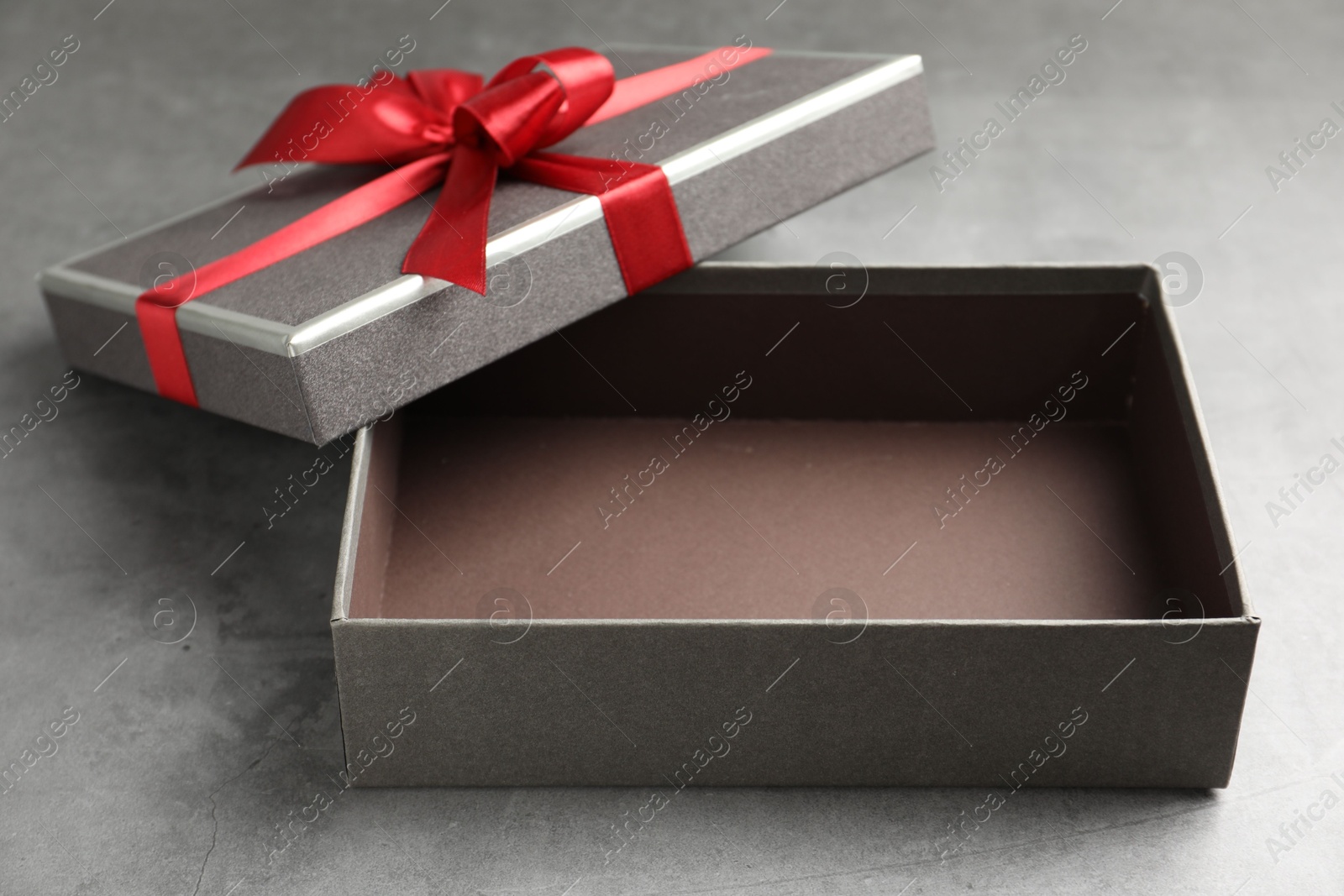 Opened gift box with beautiful lid on grey table, closeup Photo of Opened gift box with beautiful lid on grey table, closeup