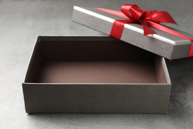 Photo of Opened gift box with beautiful lid on grey table, closeup