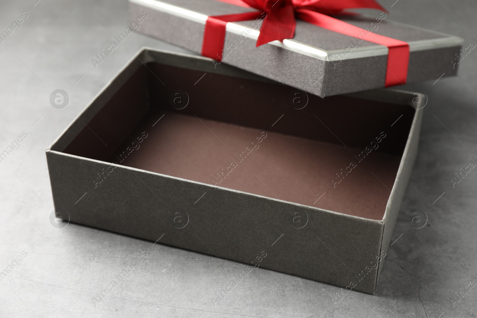 Photo of Opened gift box with beautiful lid on grey table, closeup