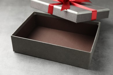 Photo of Opened gift box with beautiful lid on grey table, closeup