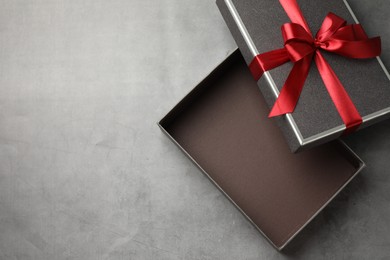 Photo of Opened gift box with beautiful lid on grey table, top view. Space for text