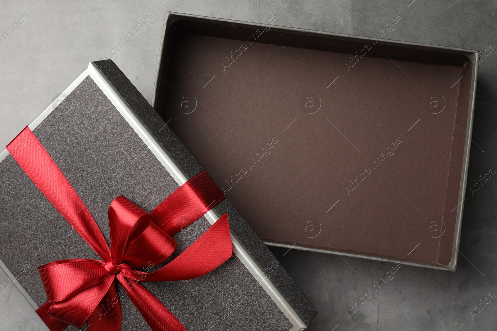 Opened gift box with beautiful lid on grey table, top view Photo of Opened gift box with beautiful lid on grey table, top view
