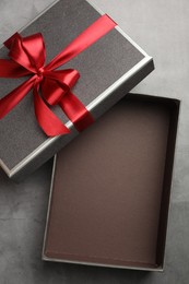 Photo of Opened gift box with beautiful lid on grey table, top view