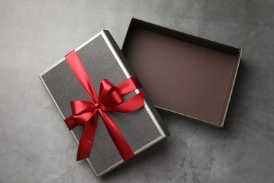 Photo of Opened gift box with beautiful lid on grey table, top view