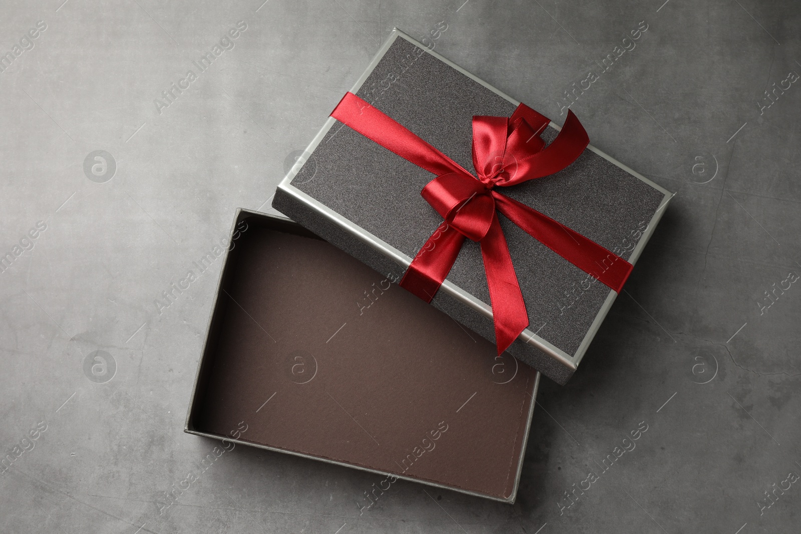 Opened gift box with beautiful lid on grey table, top view Photo of Opened gift box with beautiful lid on grey table, top view